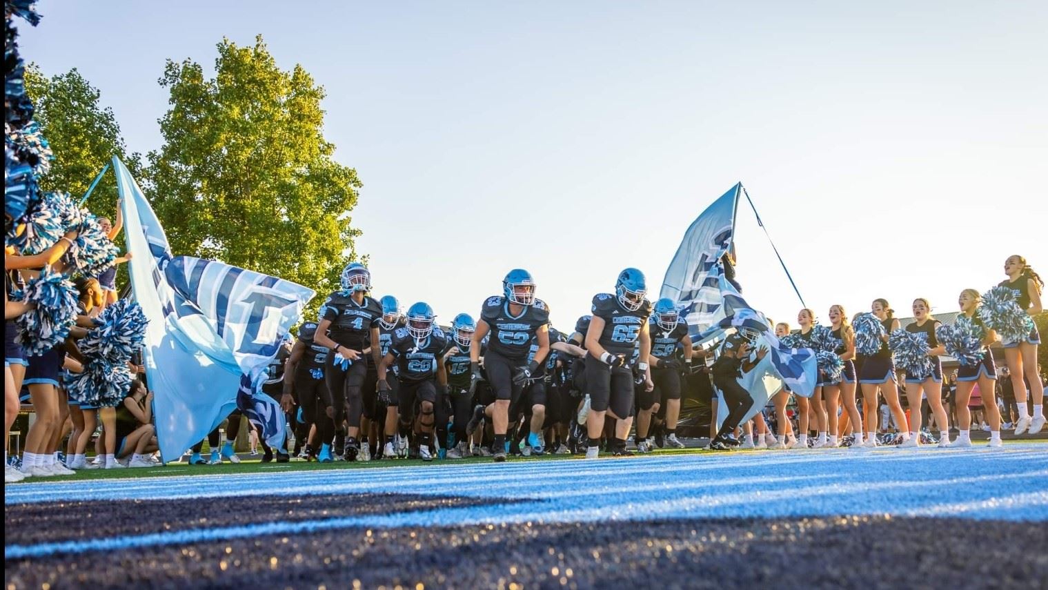 The Cougar football team breaks through the opening banner and rushes onto the field.